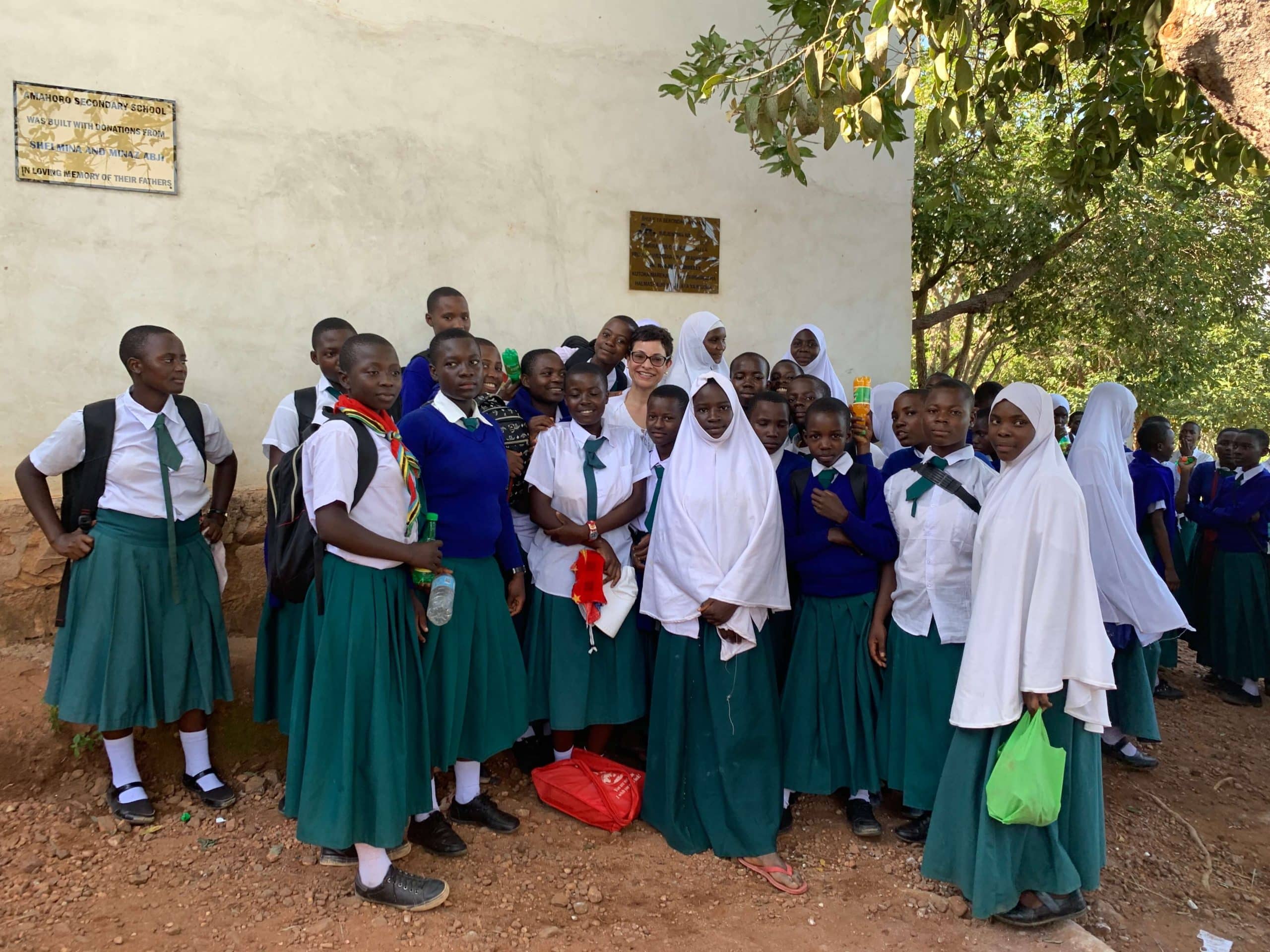 Shelmina standing with young students in Tanzania.